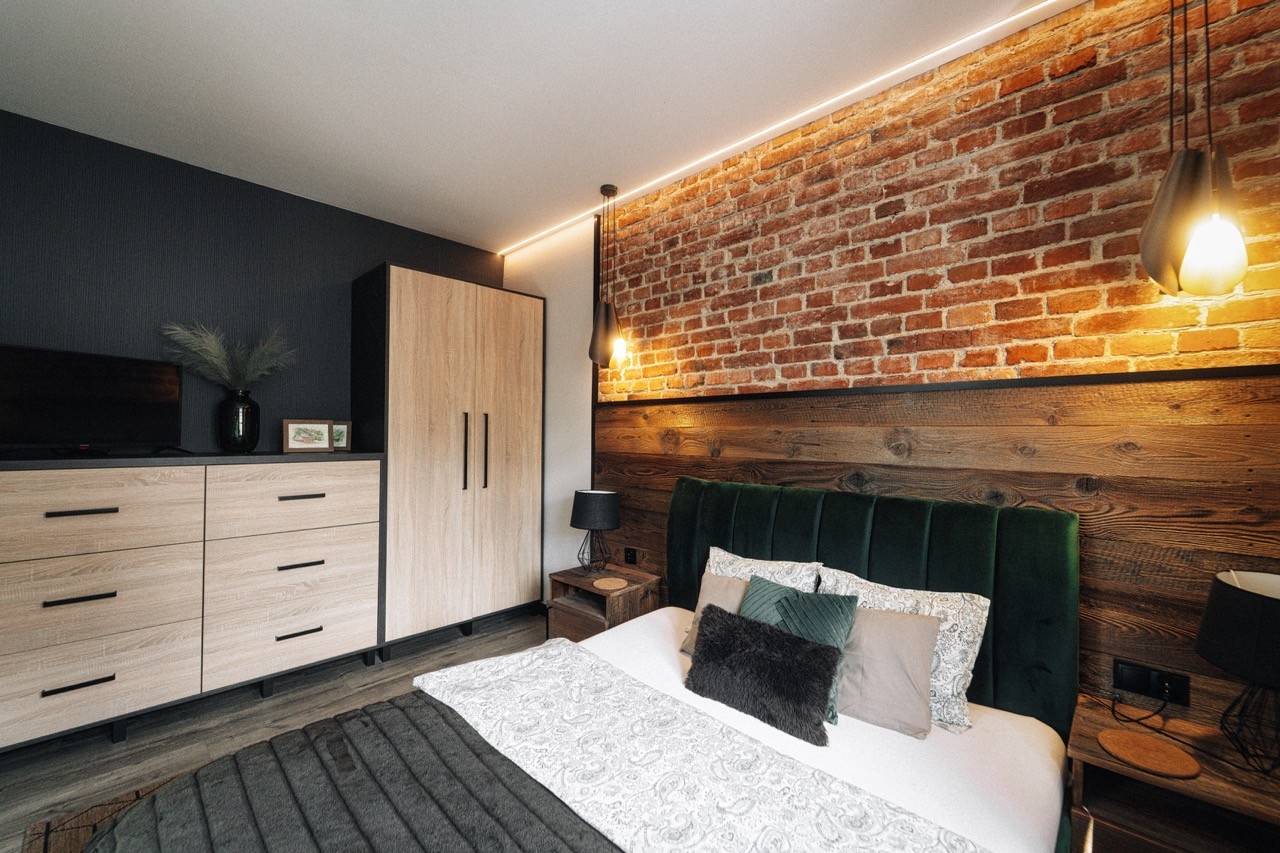 Sypialnia apartamentu Rysy z łóżkiem i ścianą z cegły