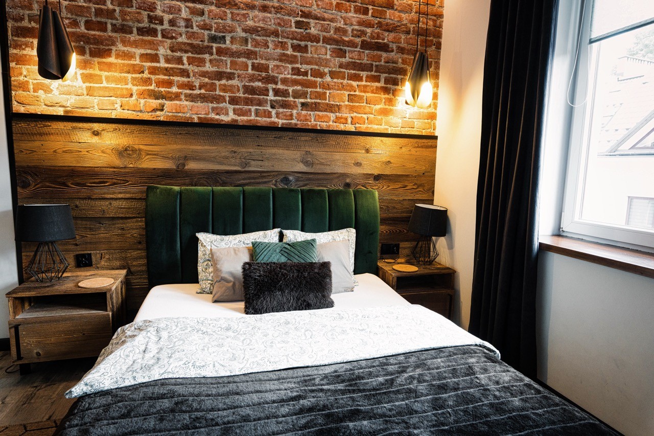 Łóżko w apartamencie Rysy na tle ceglanej ściany i drewnianego zagłówka