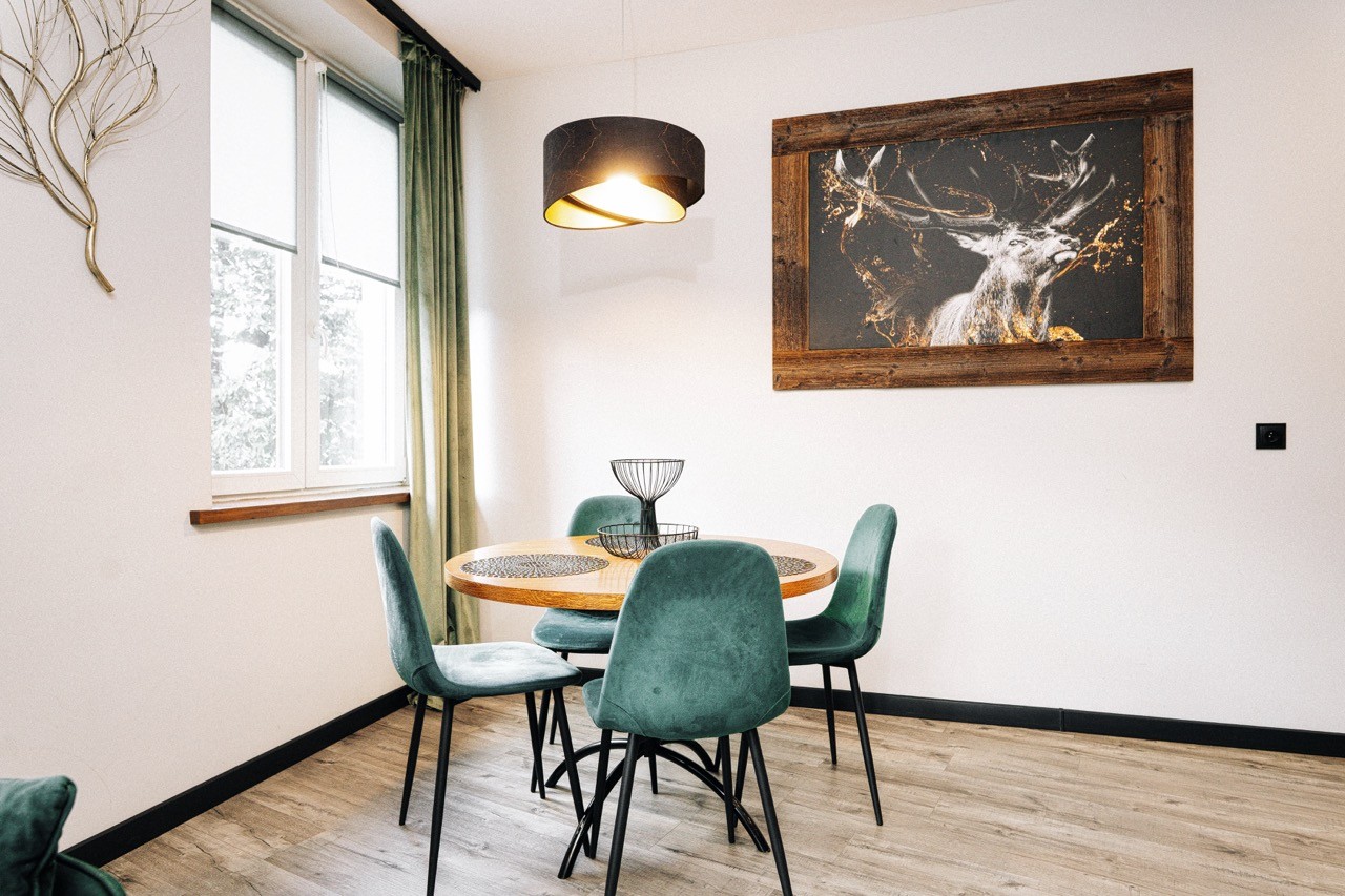 Jadalnia apartamentu Rysy z okrągłym stołem i zielonymi krzesłami