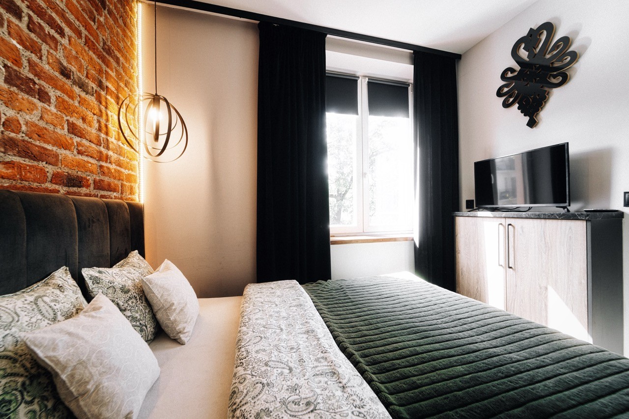 Przytulna sypialnia z ciemnozieloną narzutą w apartamencie Watra