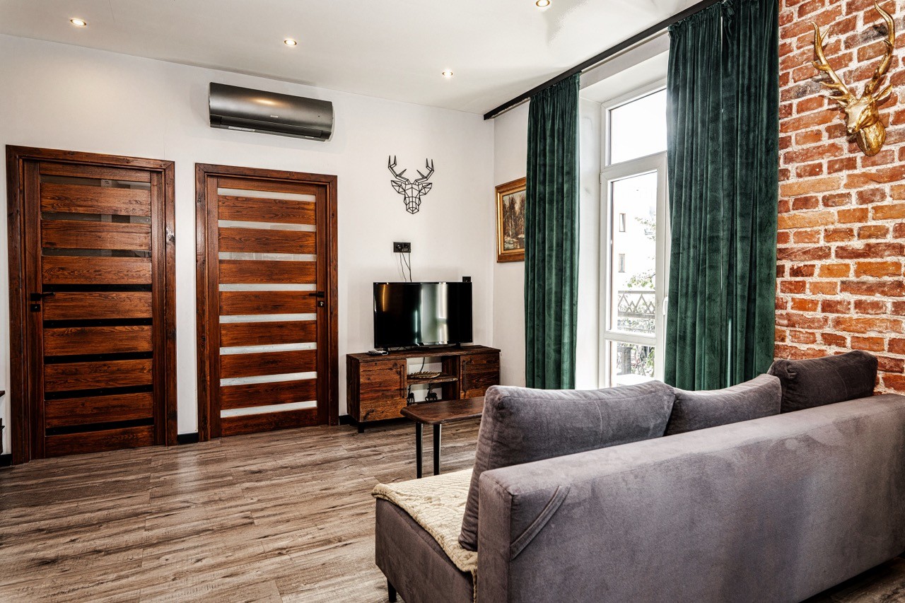 Wypoczynkowa część salonu z sofą i wyjściem na balkon w apartamencie Watra