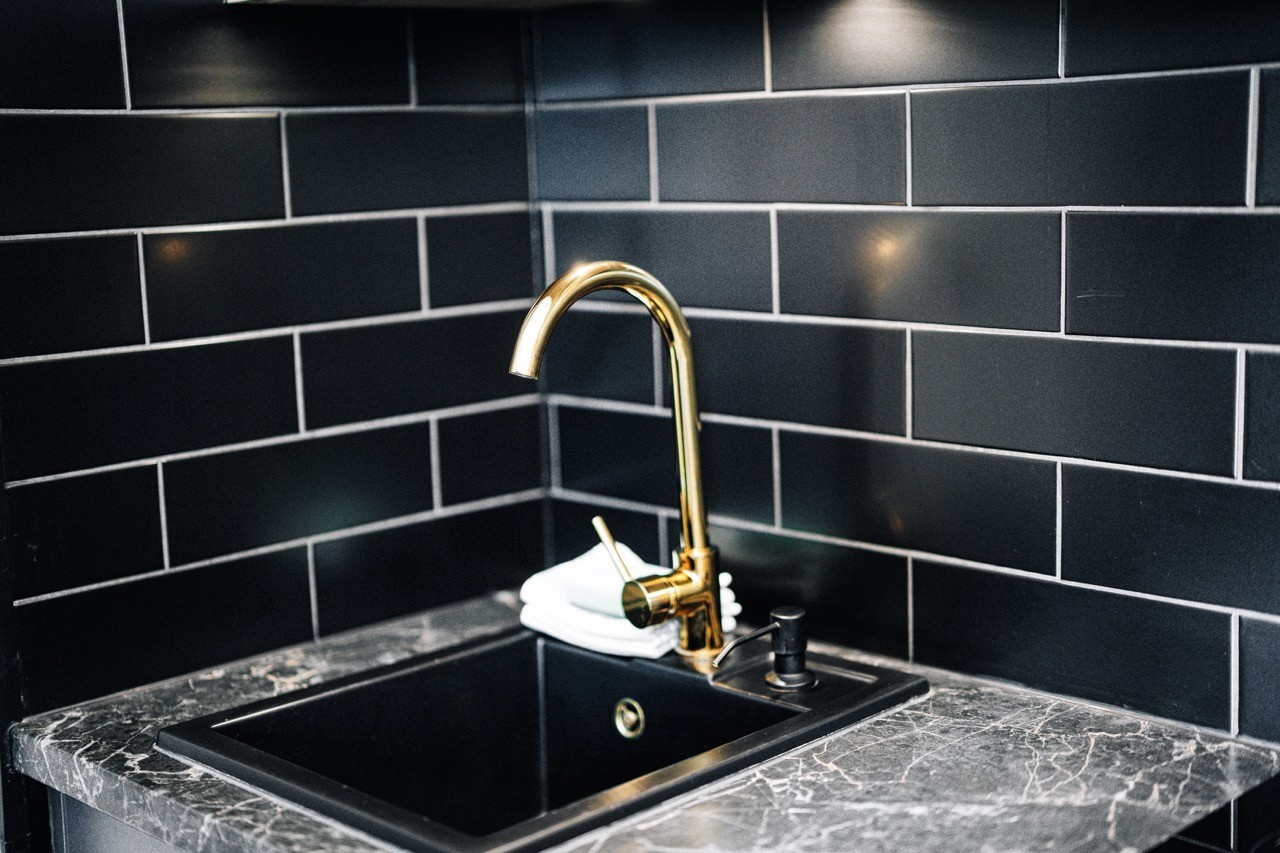 Kuchenny zlew ze złotą baterią i marmurowym blatem w apartamencie Watra